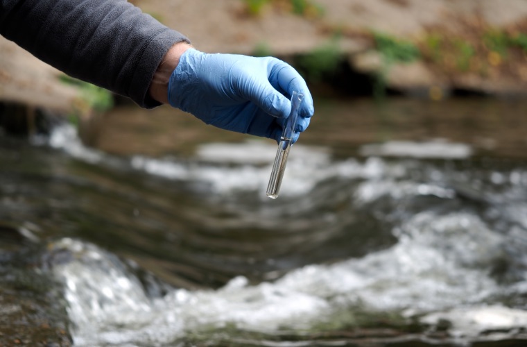 Gloved hand holding sample of Water