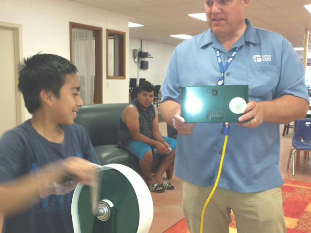 Child spinning handles to generate electricity and turn on lightbulb.